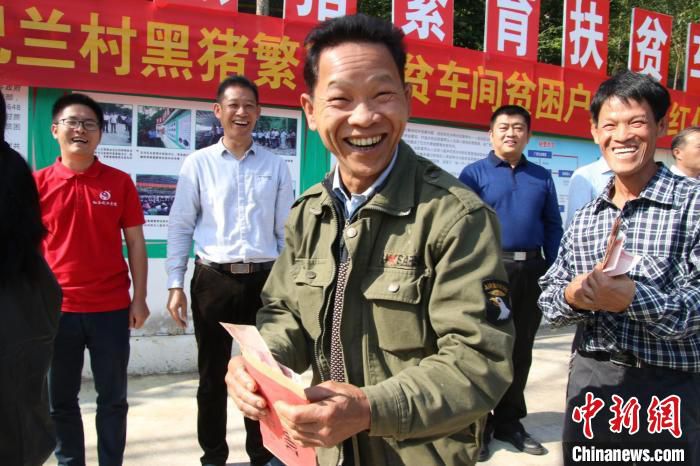 崇左市大新县那岭乡巴兰村通过黑猪繁育扶贫车间大力发展村集体经济。图为贫困户赵国领到分红开开心不已。　广西大新县委组织部供图
