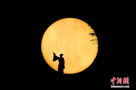资料图：图为演员在人工月亮前吟诵唐诗宋词。杨华峰 摄