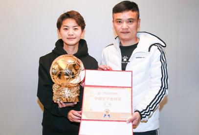 王霜从她青少年时期的教练、武汉东西湖区足球青训教练的韩建手中接过中国女子金球奖奖杯。中国金球奖组委会供图