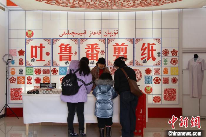葡萄沟景区内的非遗集市，游客体验剪纸技艺。　苟继鹏 摄
