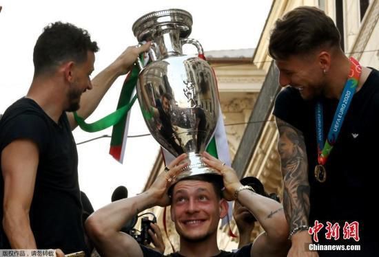 资料图：2021年7月12日，意大利国家足球队夺得欧洲杯冠军第二天，在罗马举行冠军奖杯游行。图为意大利球员将奖杯“加冕”在头顶。