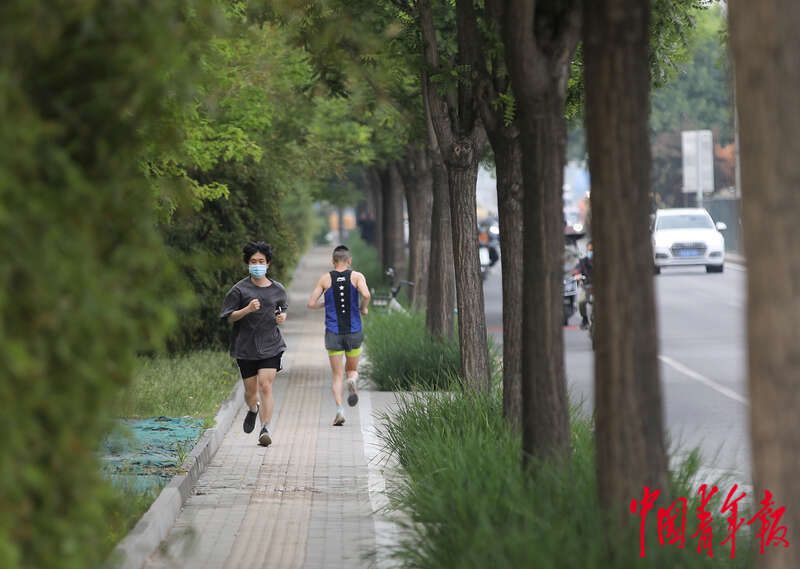 图为5月19日，北京市东四环辅路边的人行道，两名年轻人正在跑步锻炼身体。中青报·中青网记者 陈剑/ 摄