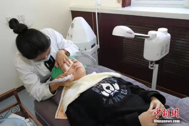 图为医师正在用冷热喷蒸脸器对一位女大学生进行脸部皮肤的祛痘清洁护理。 中新社记者 张道正 摄