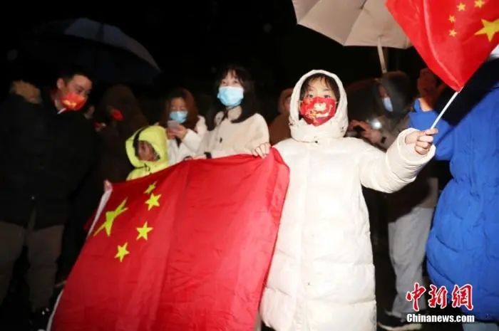 2月7日晚，夺得亚洲杯冠军的中国国家女子足球队一行抵达上海。在隔离酒店外，冒雨前来的不少球迷高举国旗，欢迎中国女足凯旋而归。中新社记者 张亨伟 摄
