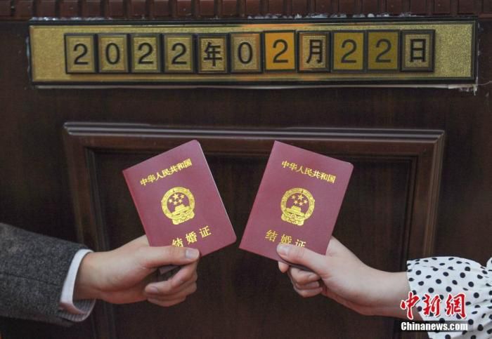 资料图：一对新人拿结婚证和日期数字拍照。 中新社记者 王刚 摄

