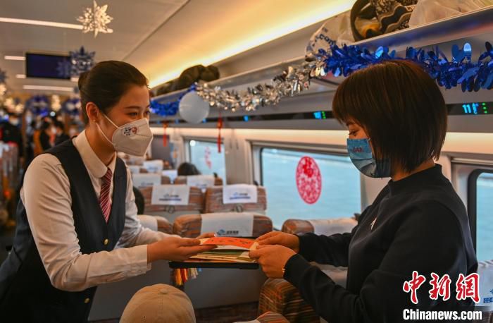 乘务员向旅客展示、赠送了以奥运为主题的绘画作品、书签和吉祥物。　于海洋 摄