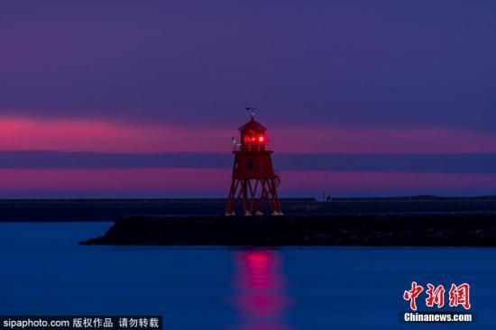 资料图：近日，英国北希尔兹泰恩茅斯码头出现瑰丽日出景观，朝霞与彩虹遥相呼应，画面唯美。图片来源：Sipaphoto 版权作品 请勿转载