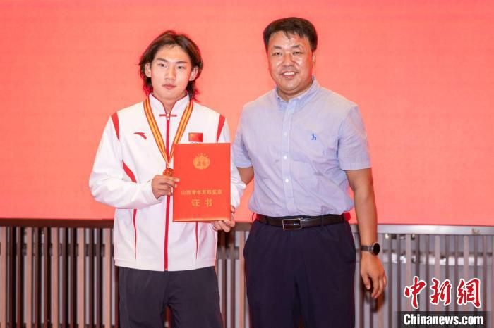 共青团山西省委副书记吴兴为苏翊鸣颁发“山西青年五四奖章”与证书。　山西省体育局供图