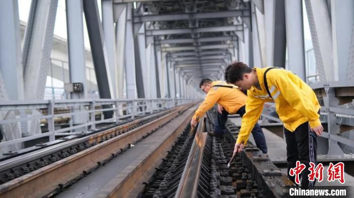 职工对钢梁桥明桥面桥枕敲击检查 莫忘回归 摄
