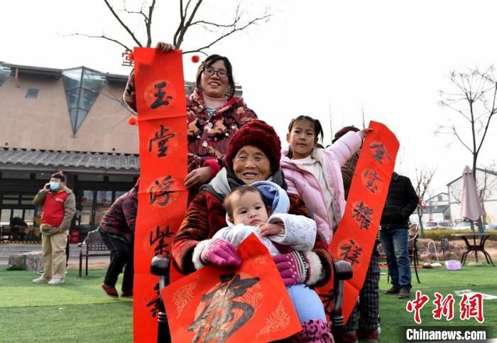 抱着重孙女的87岁周老太喜领春联福字。　朱志庚 摄