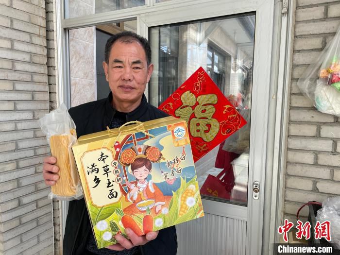 图为曹克尊展示自己做的玉米面条及“中国健康好乡村”组委会为玉米面条设计的包装礼盒。　李晗雪 摄