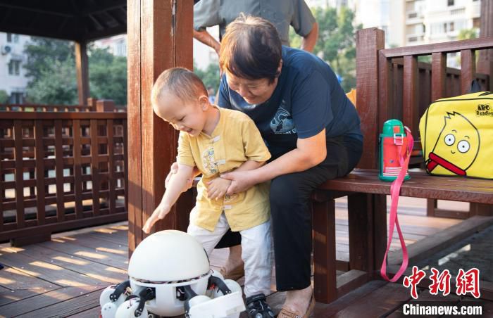 “X-Spider”养老陪伴六足轮足式AI机器人与老人、小孩互动。　王雨桐供图