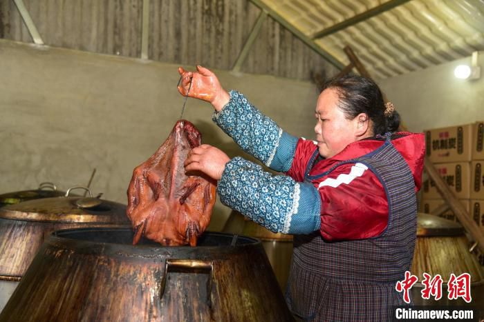 农户将烘烤好的腊鸭在炉中取出。　王以照 摄