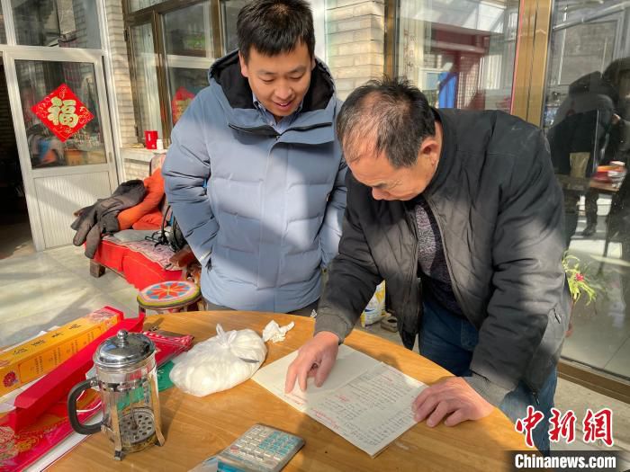 图为曹克尊正与杨立钦核对账目，结清玉米面条的相关款项。　李晗雪 摄
