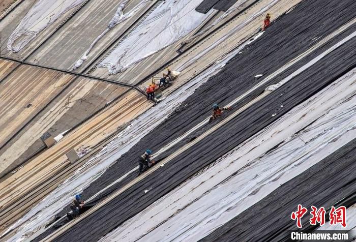 施工人员正在上库大坝坝面进行保温材料覆盖作业(资料图) 沈志华 摄