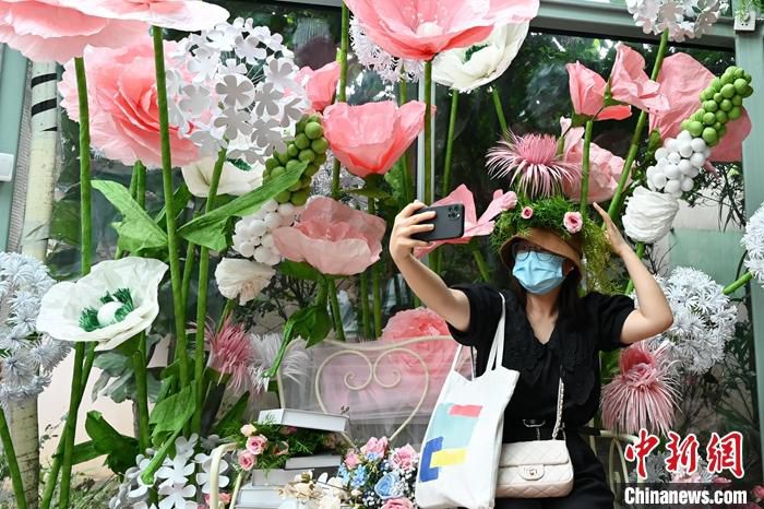 6月30日，广东广州，一名游客在正佳雨林生态植物园的“爱丽丝的玻璃房”展区自拍。中新社记者 陈楚红 摄
